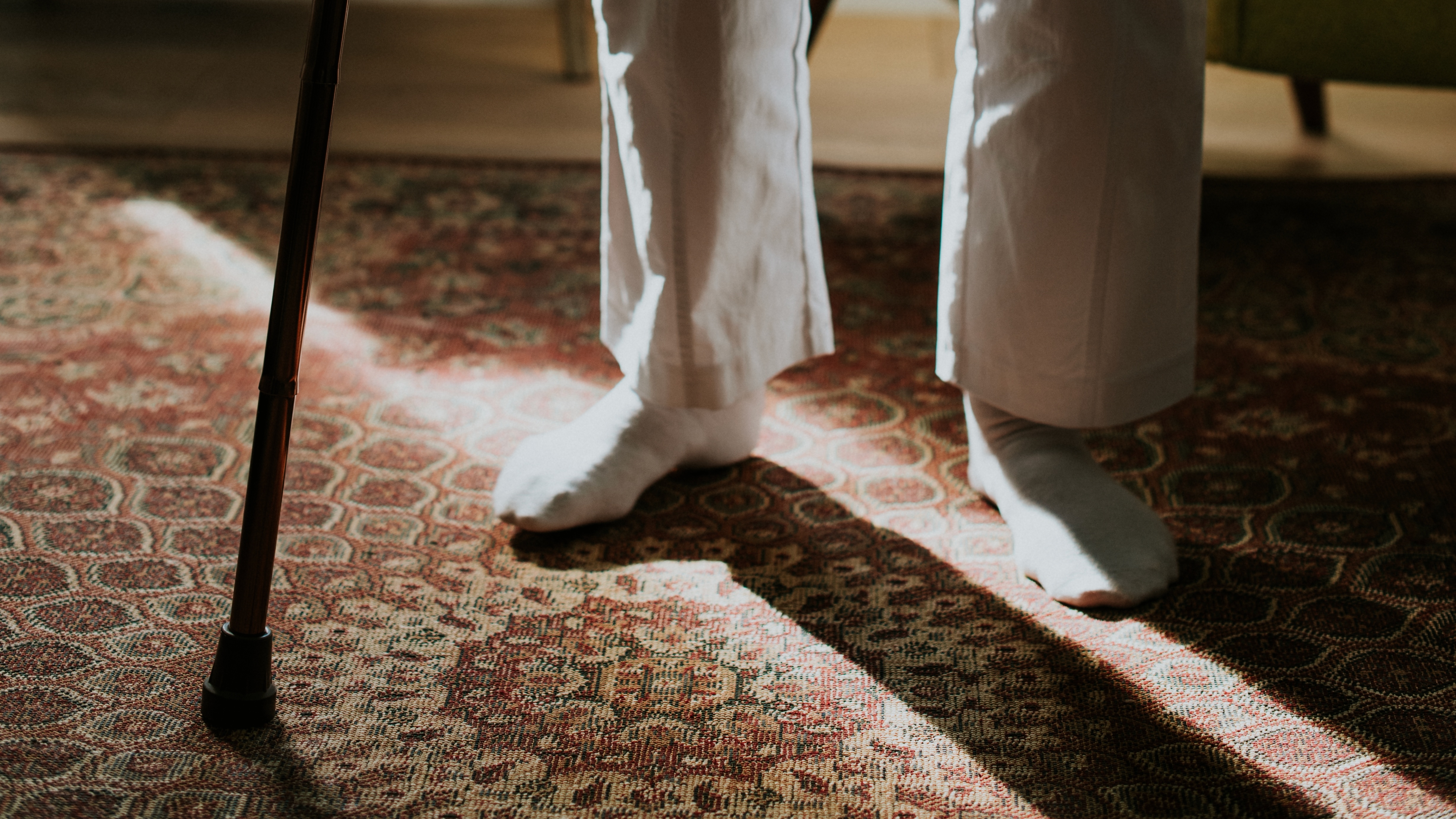 Older adult wearing socks while using a walking stick – sock aids help elderly parents with limited flexibility or balance to put on socks independently without bending or straining.