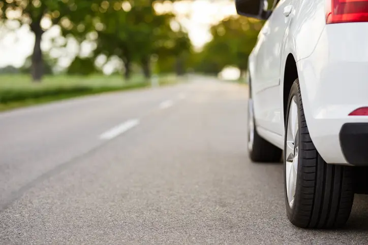A road with a white car driving down it