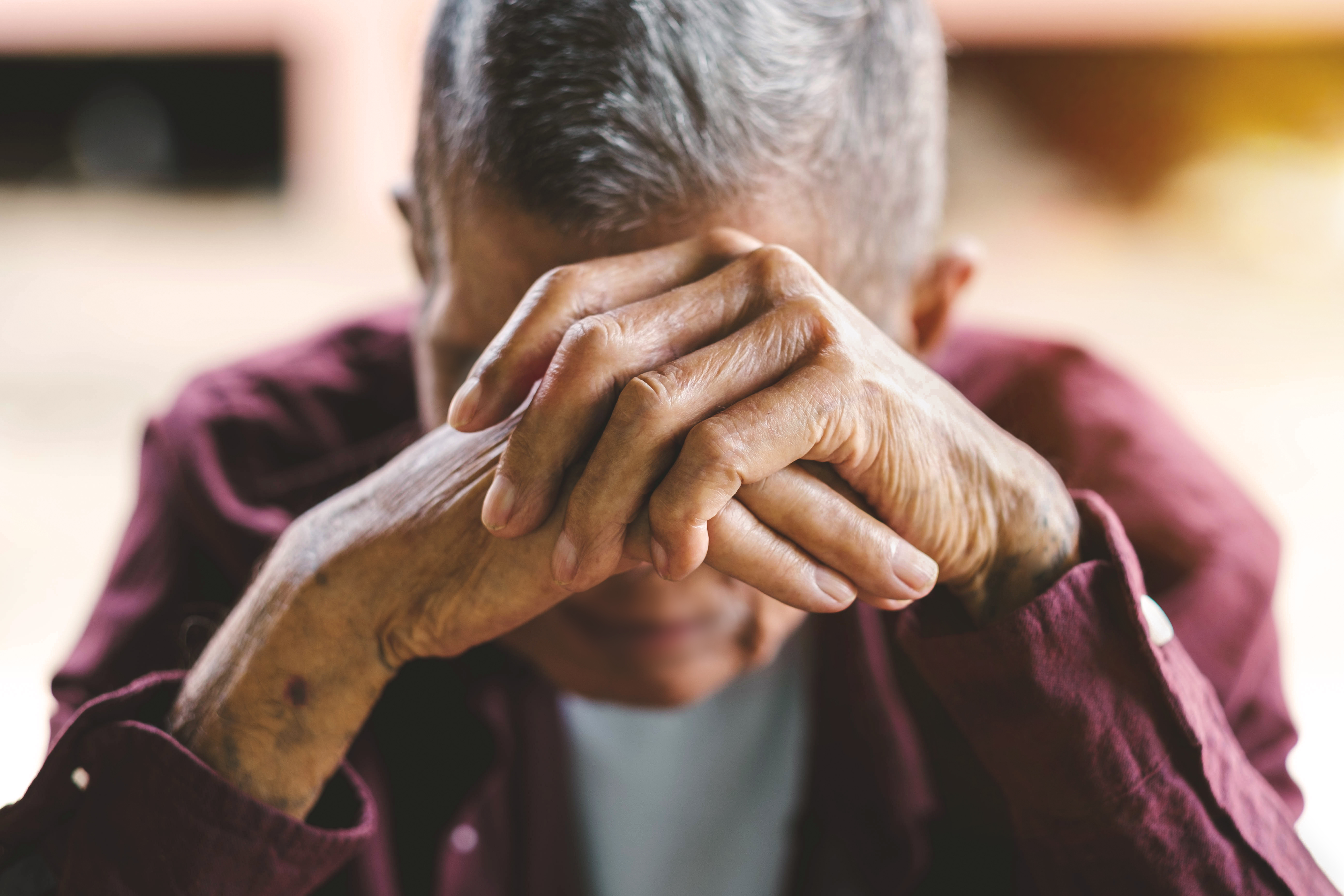 An elderly man with his head in his hands. Represents feelings of loneliness or depression, both of which an elderly parent could be.