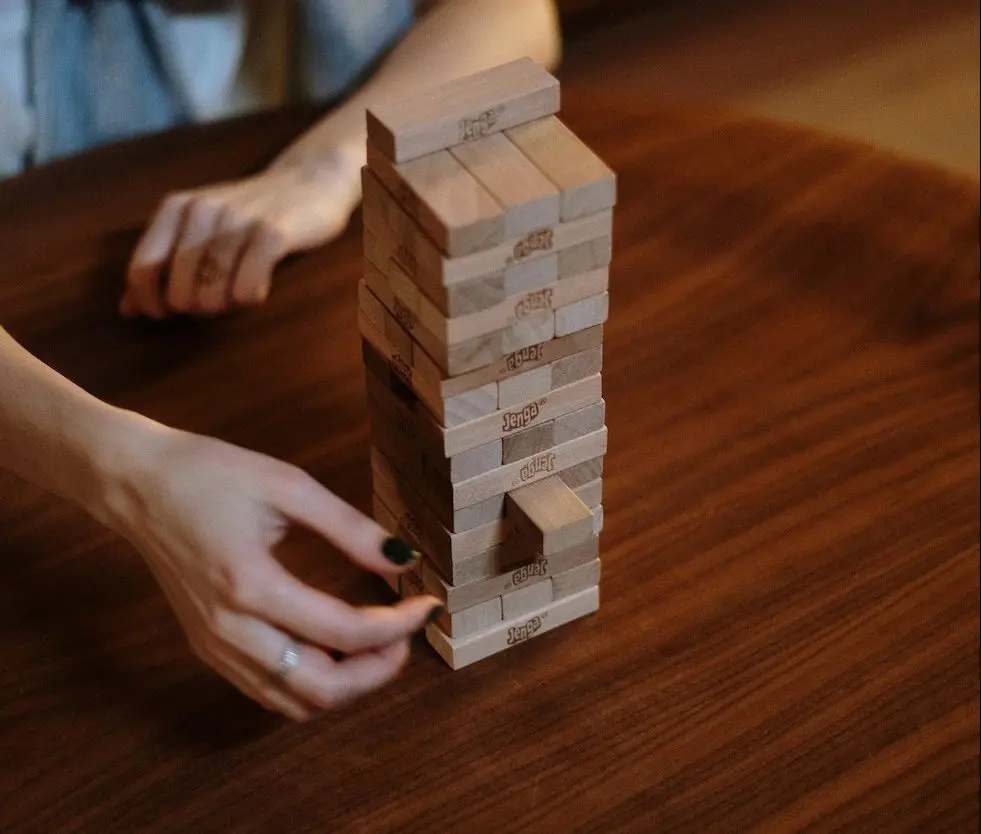 Wooden Jenga blocks with a middle aged woman taking out a piece