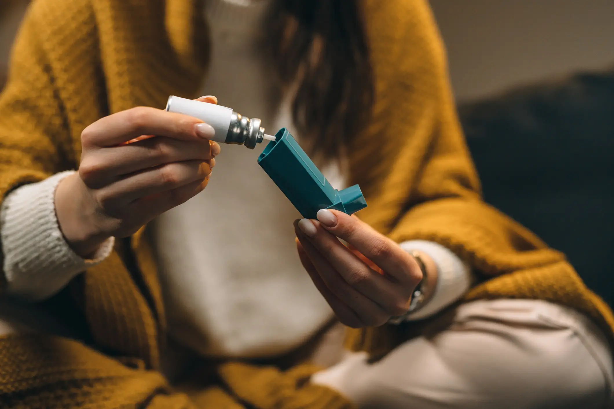 woman sitting down and looking at an inhaler
